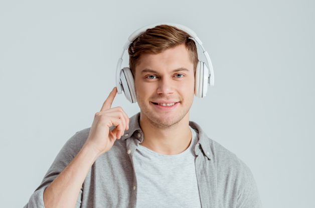 Gutt med hodetelefoner smiler og peker mot øret